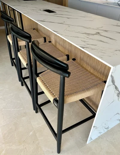 Nowoczesny bar z jasnym marmurowym blatem i ciemną szafką pod spodem, tworzący elegancki kontrast.